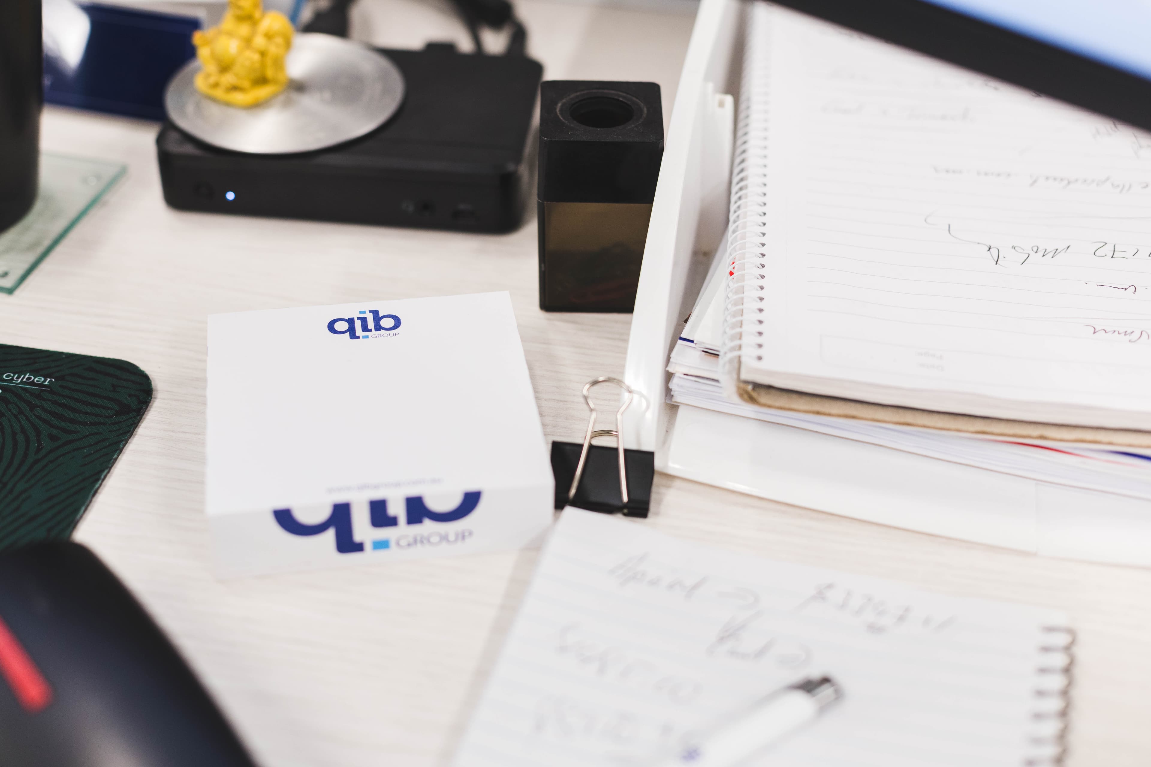 QIB Group branded notepads and stationery on an office desk