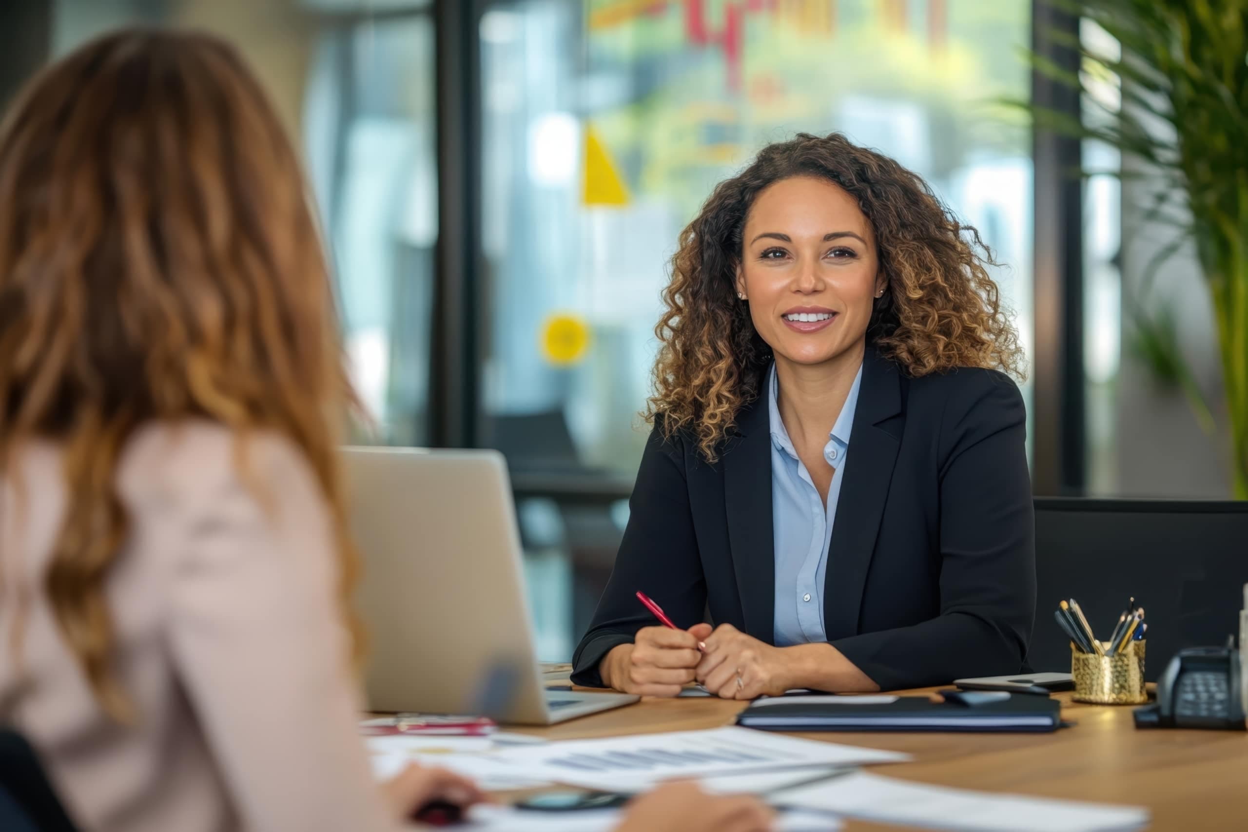 Insurance broker consulting with a client at her desk in a modern office