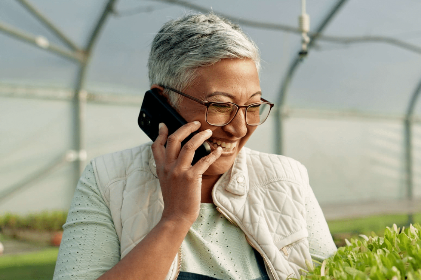 Woman on phone call laughing in greenhouse