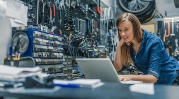 Woman in toolhouse looking at laptop